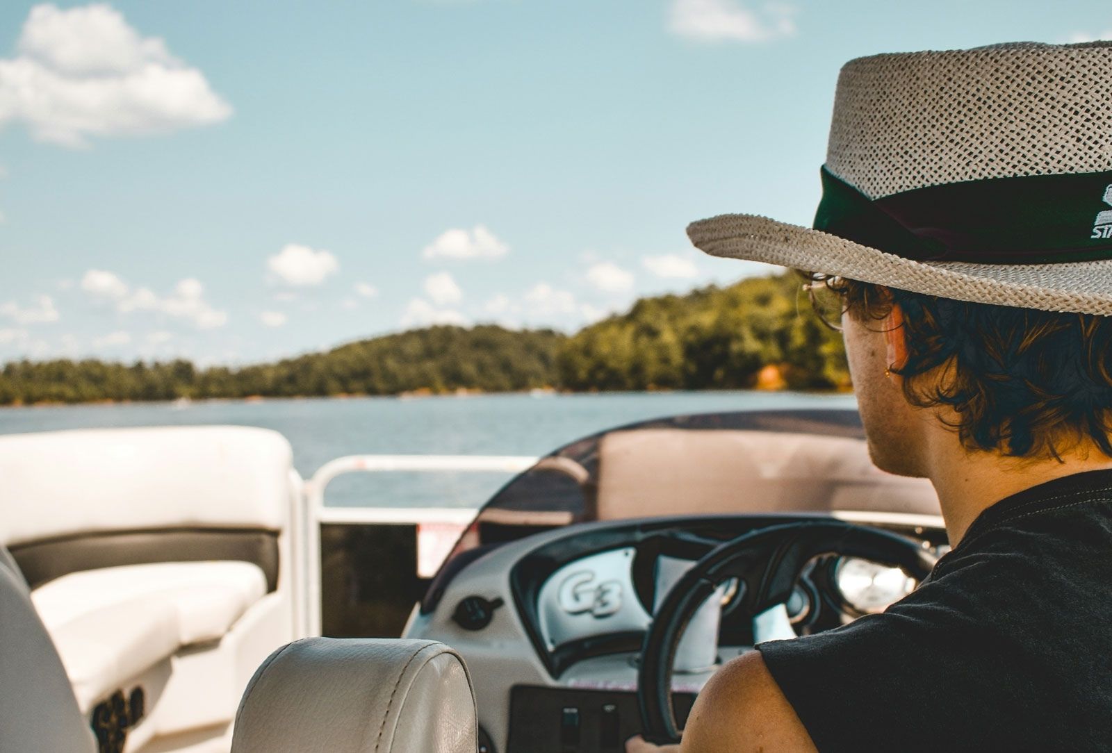 view of a mans back as he drives boat looking at water