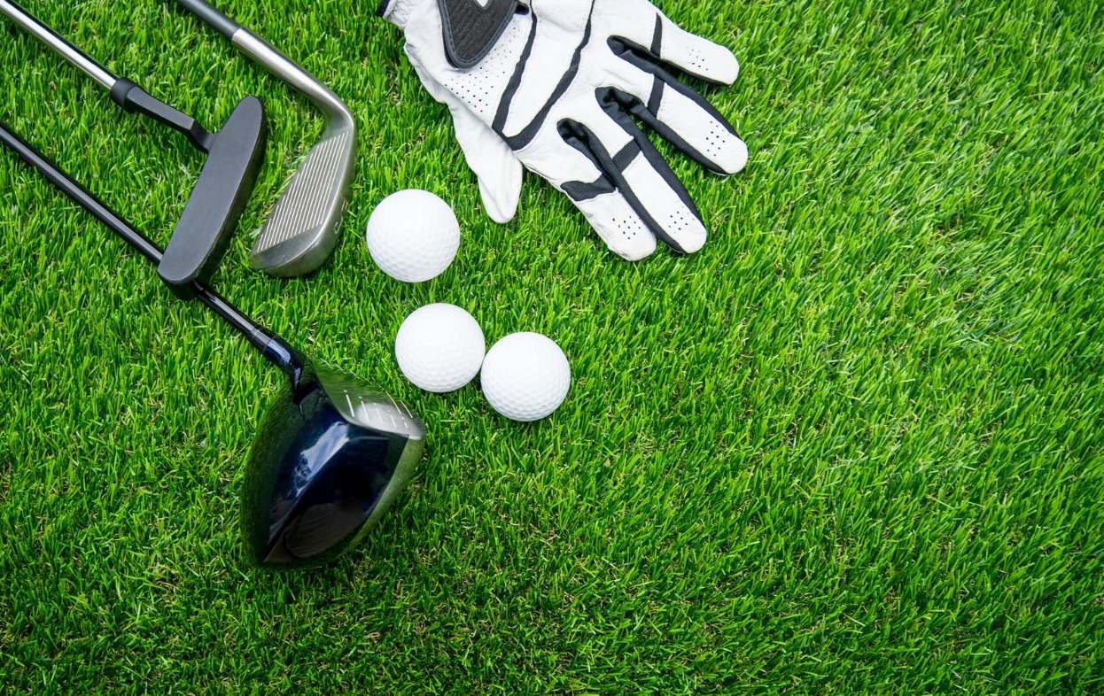 golf glove with balls and golf clubs on grass