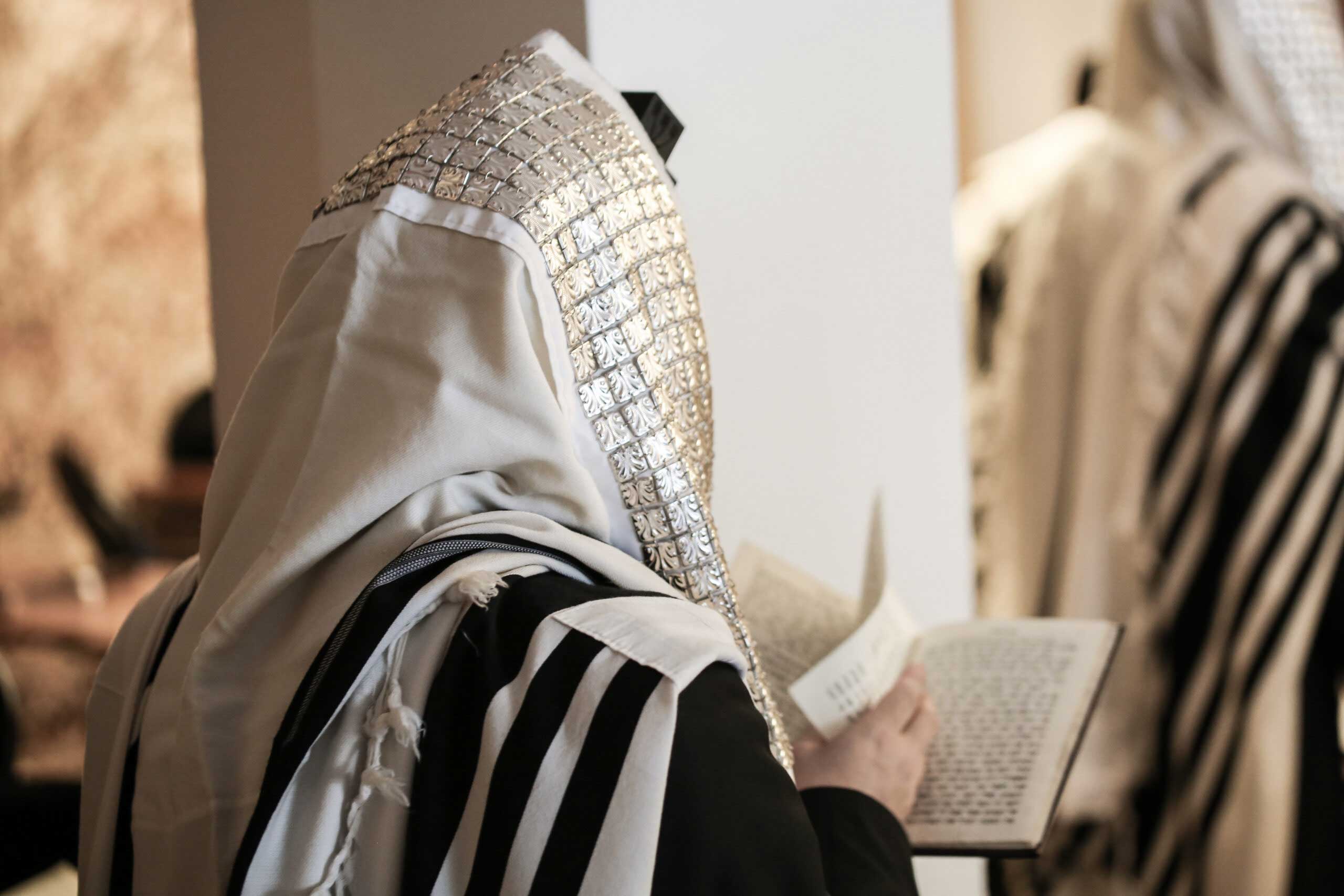 Person wearing a tallit, holding a prayer book for passover in florida at villatel orlando resort